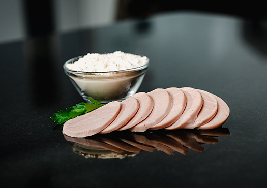 Angerichtete Wurstscheiben mit Petersilie und einem Schälchen mit Proteinpulver im Hintergrund