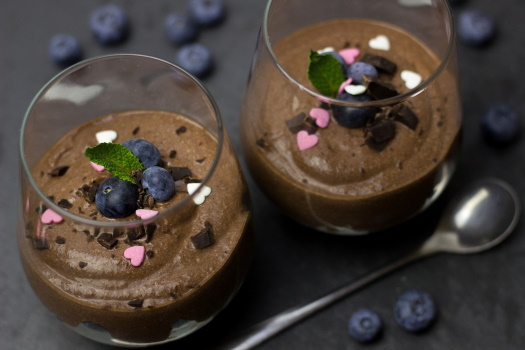 Fettreduzierte Mousse au chocolat mit Heidelbeeren gefüllt in Gläsern