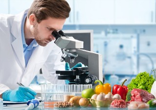 Wissenschaftler untersucht am Mikroskop Lebensmittel