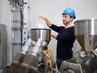 Fraunhofer IVV Mitarbeiter schüttet Kunststoffgranulat in eine Anlage.