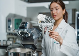 Aufgeschlagener Proteinschaum am Rührer einer Rührmaschine, der von einer Wissenschaftlerin aus seine Stabilität optisch überprüft wird