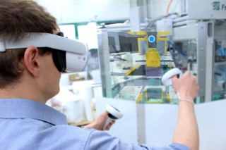 Ortsflexible VR-basierte Qualifikation von Maschinenbedienenden Abbildung eines Mitarbeiters, der mittels VR-Brille virtuell in eine Anlage zur Herstellung tiefgezogener Verpackungen schaut.