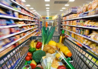 Gefülter Einkaufswagen zwischen Regalen