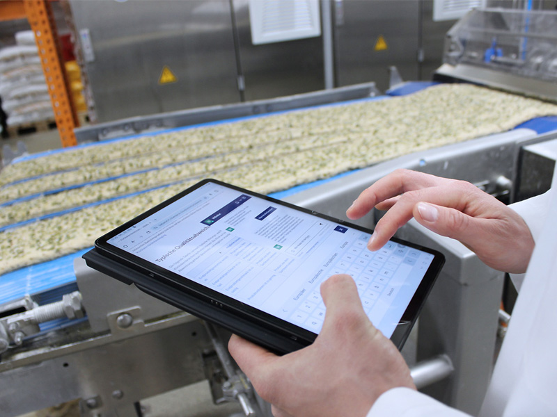 Sächsischer Staatspreis für Transfer 2025 Zwei Hände bedienen Tablet vor Fließband