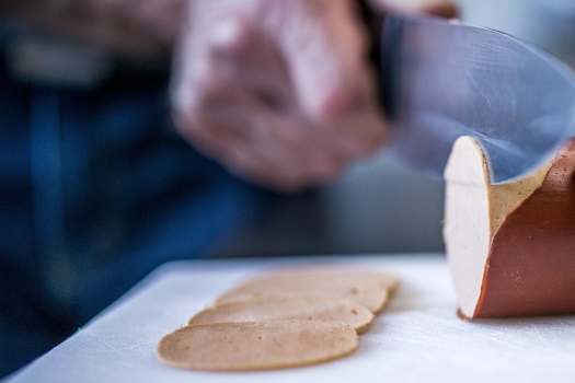 Vegane Wurst wird mit Messer in dünne Scheiben geschnitten