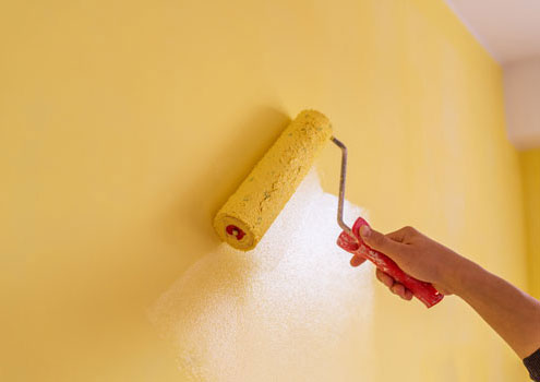 Eine Wand wird mit Dispersionsfarbe mit Hilfe einer Farbrolle gestrichen.