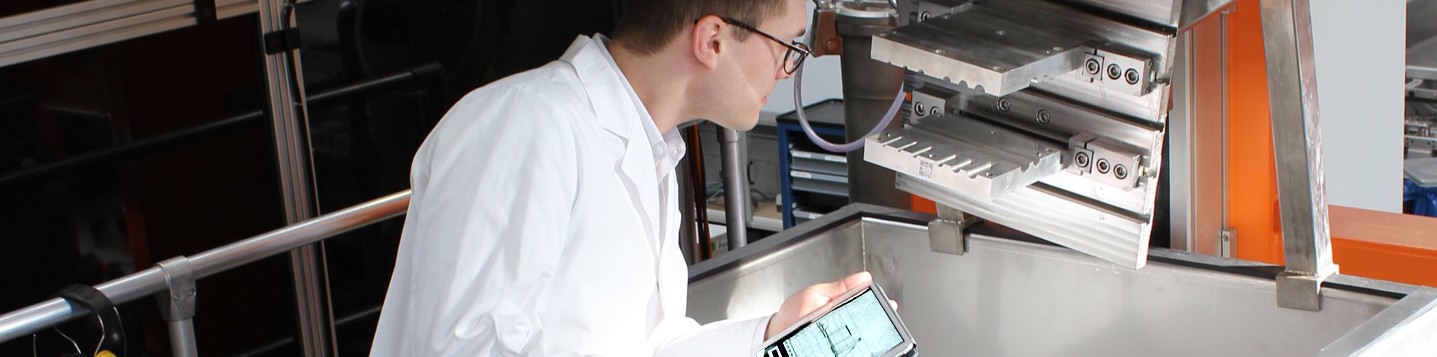 Nutzung modernster Technologien und Softwarewerkzeuge im Bereich der industriellen Bauteilreinigung Mitarbeiter prüft Erfolg der Bauteilreinigung mittels moderner Technologien