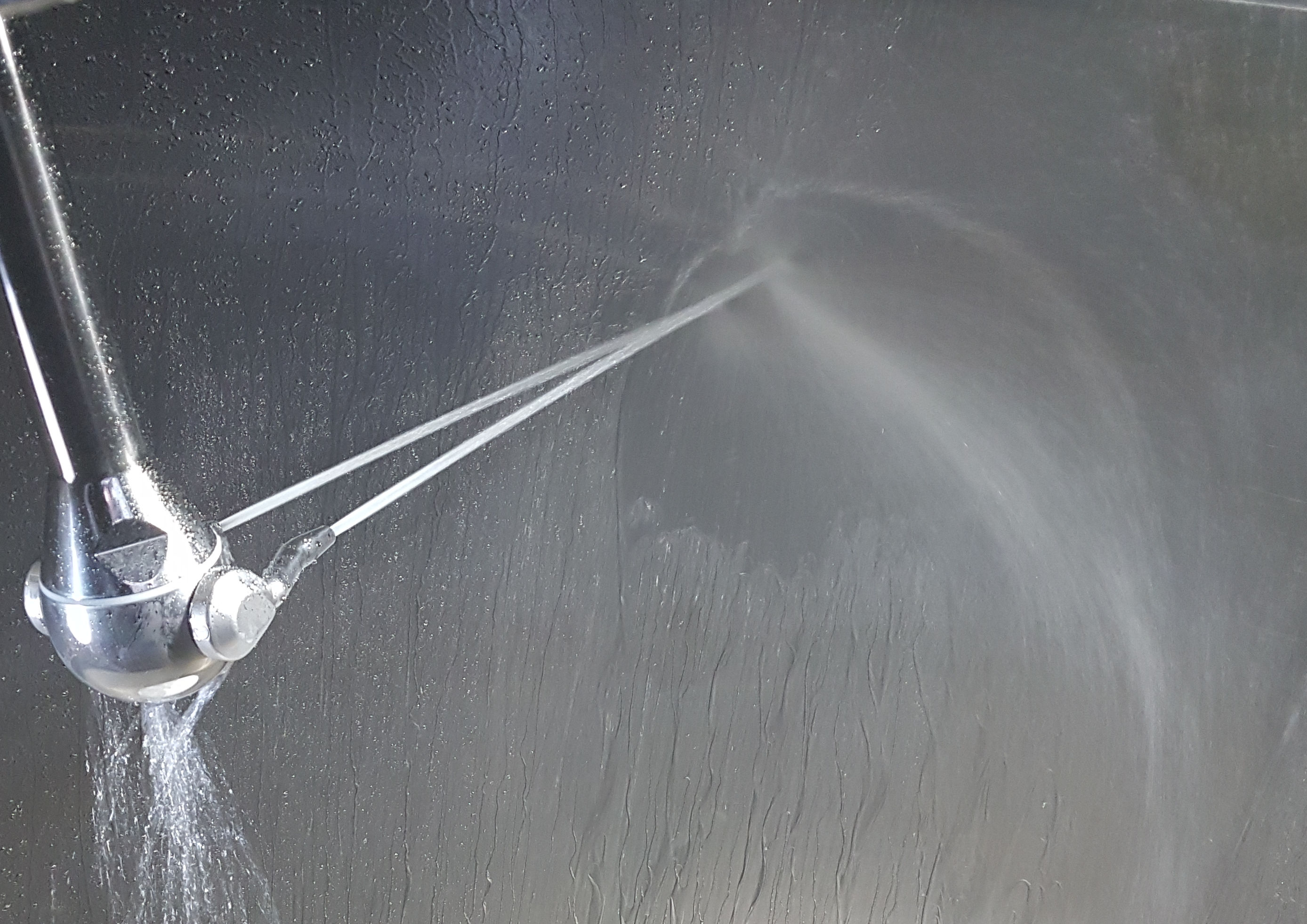 Abbildung des Düsenkopfes des Adaptive Jet Cleaners, aus dem ein Reinigungsstrahl kommte, der eine metallische Oberfläche reinigt.
