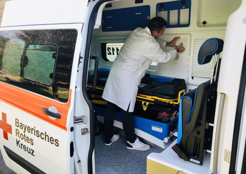 Man in white coat disinfects the inside of an ambulance.