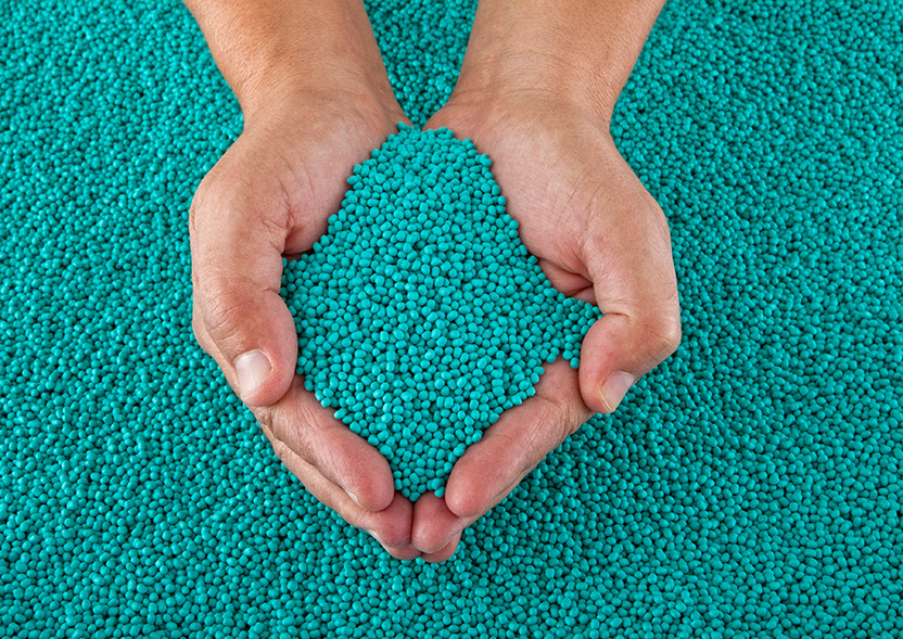 Hands hold turquoise recyclates