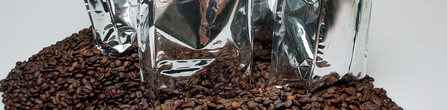 Silver coffee packaging on a pile of brown coffee beans simbolize the prediction on the shelf life of packaged coffee.
