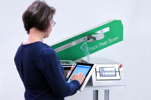 Woman stands in front of Pack Peel Scan and operates it with control element