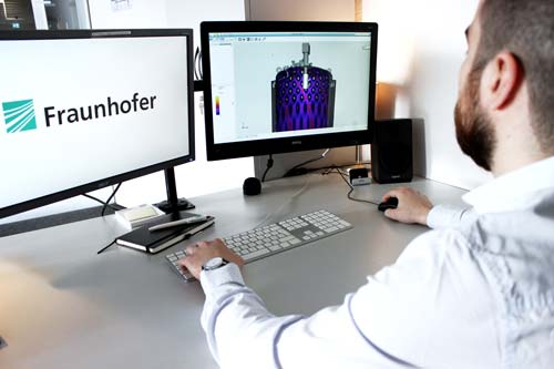 SIMKOR Simulationssoftware Mitarbeiter sitzt am Computer. Man sieht auf dem Bildschirm die SIMKOR-Simulationssoftware