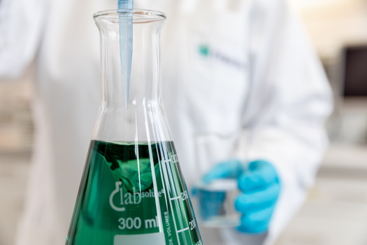 Erlenmeyer flask filled with green liquid added by employees