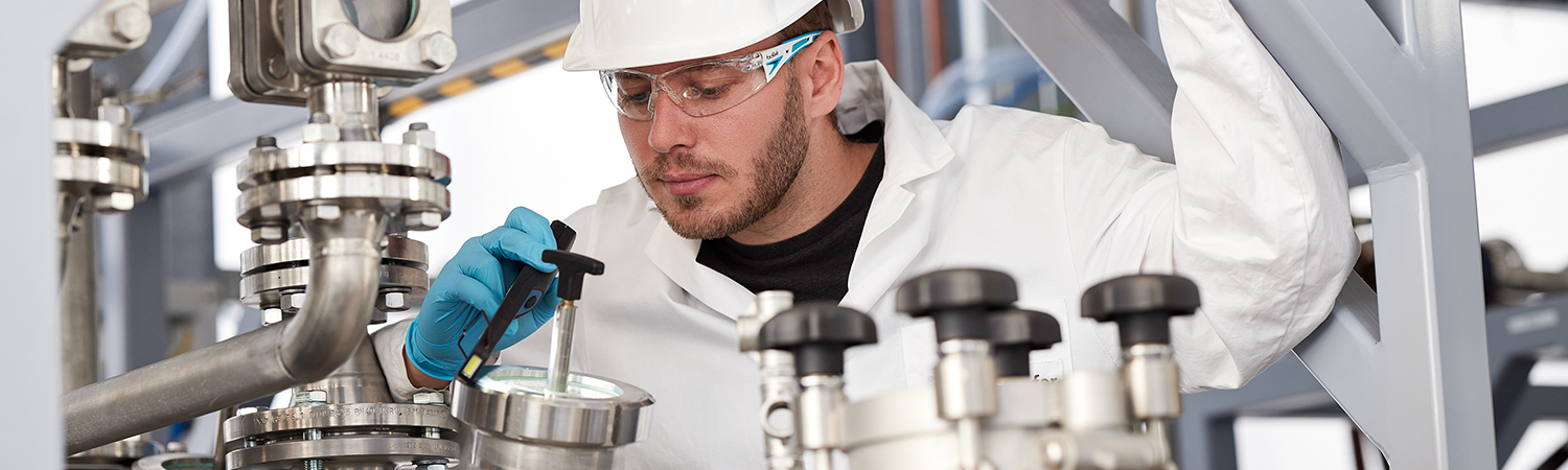 A scientist checks the recycling process via a sight glass on the reactor